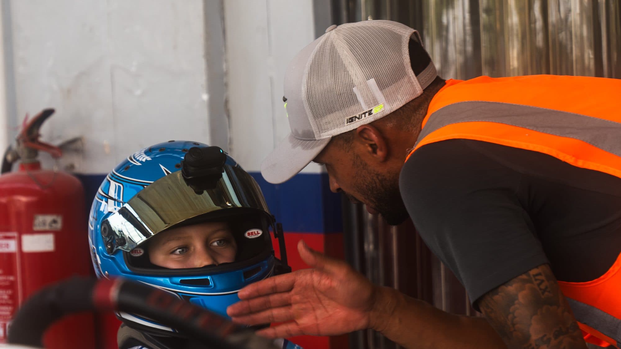 Ignite GP coach leaning in at a young driver's eye level while the driver sits in the kart