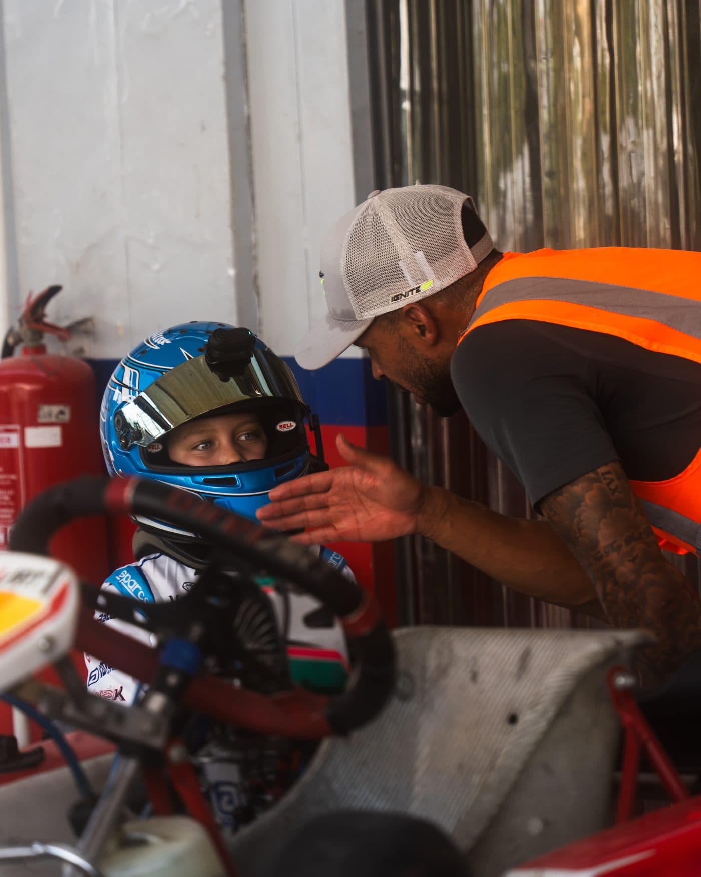 Ignite GP coach leaning in at a young driver's eye level while the driver sits in the kart