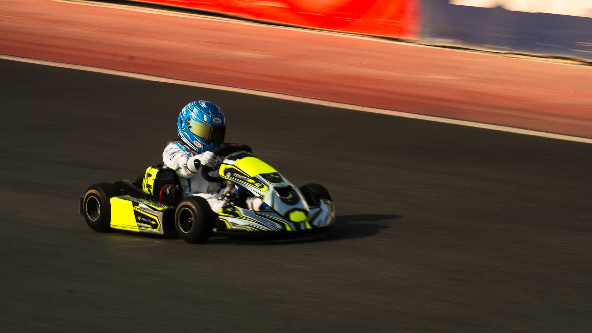 Bambino kart at full speed, panned so the track and barriers blur past