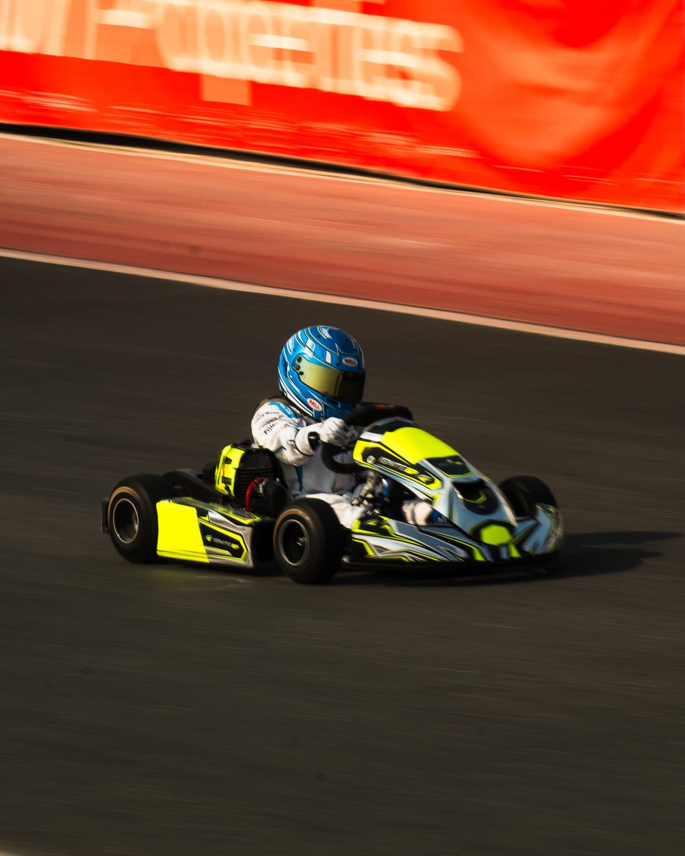 Bambino kart at full speed, panned so the track and barriers blur past