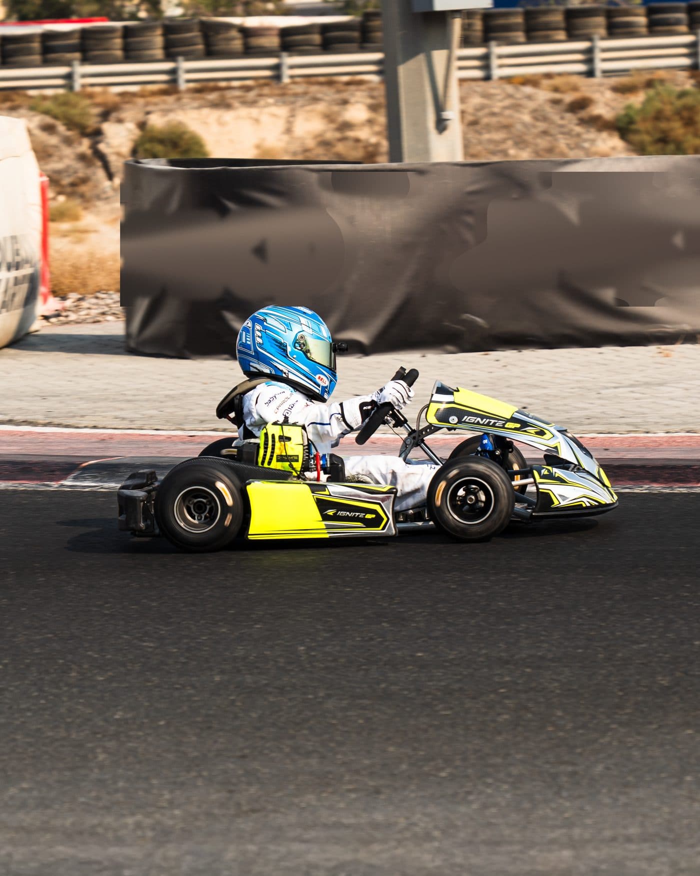 Bambino kart at speed along the barriers, desert behind the circuit