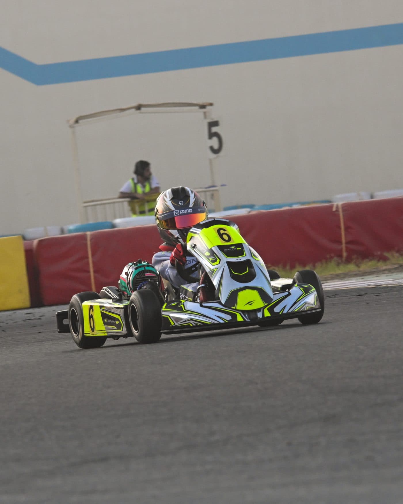 Bambino kart head-on past marshal post 5, the marshal watching from the wall