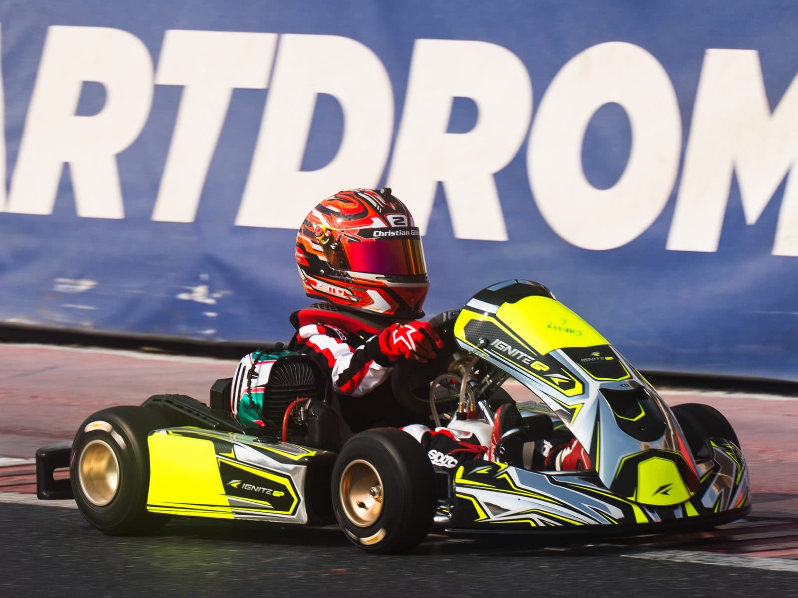Bambino driver in profile in front of the Dubai Kartdrome banner