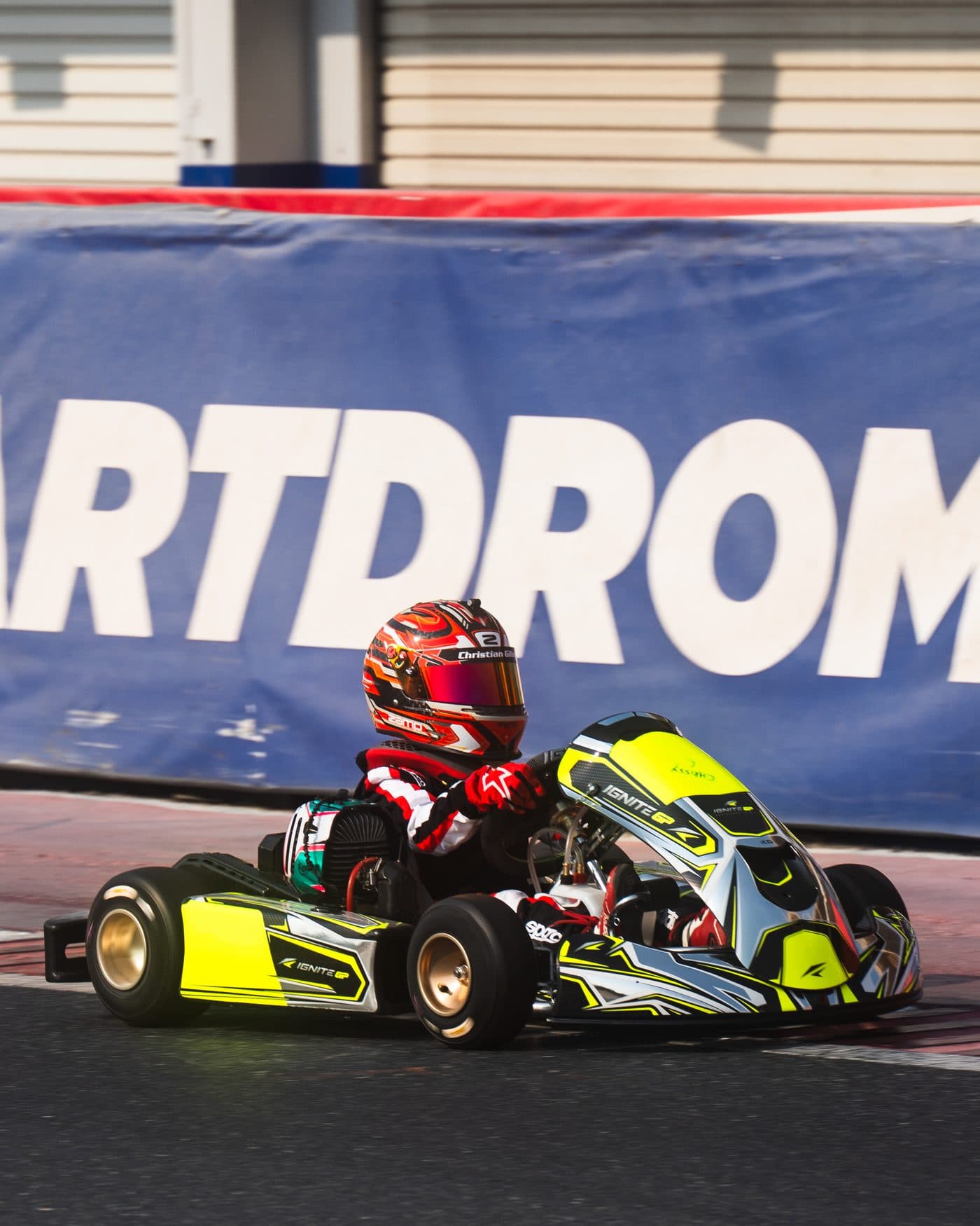 Bambino driver in profile in front of the Dubai Kartdrome banner
