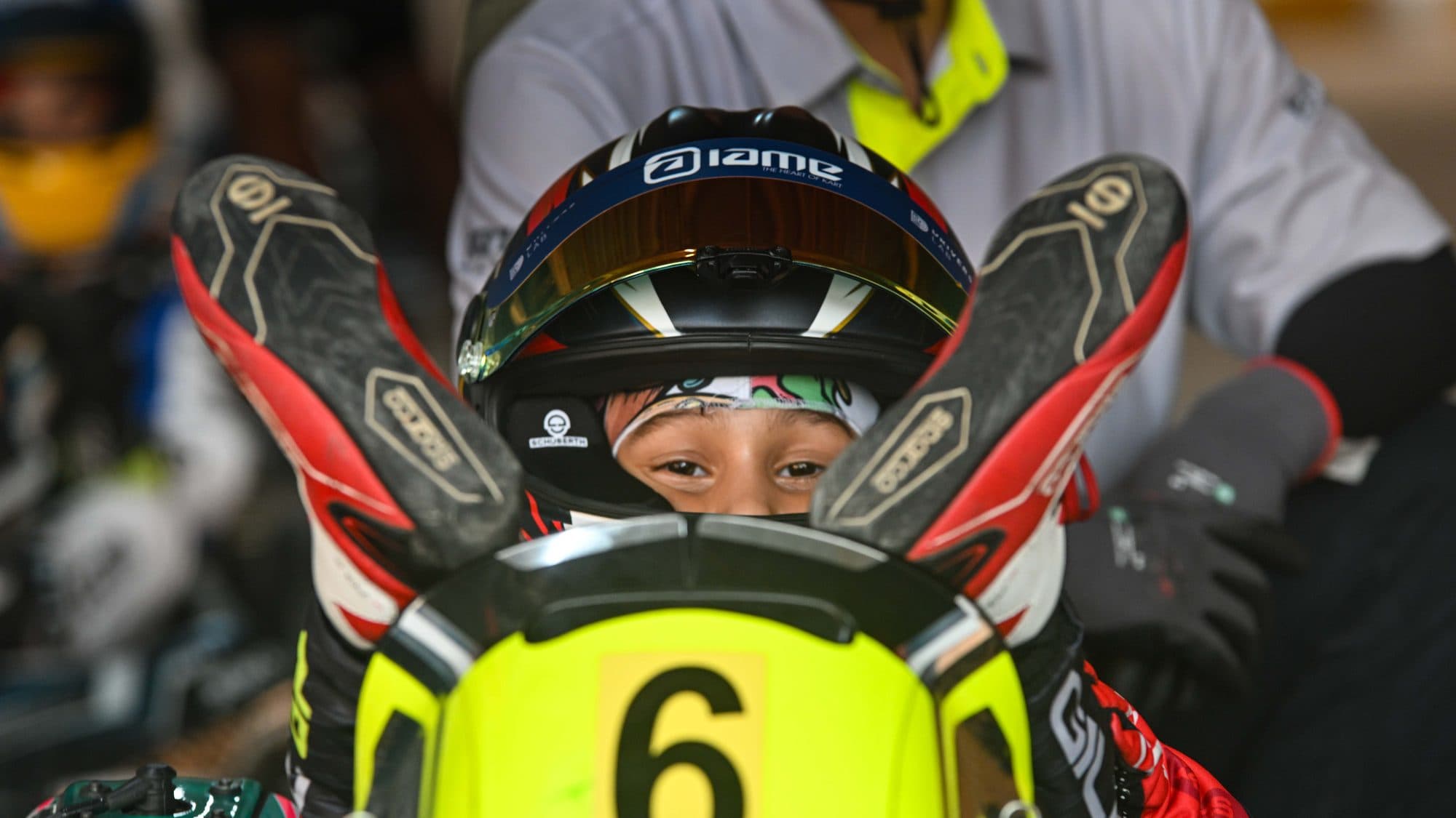 A Bambino driver's eyes through the open visor, gloves resting on the number 6 nassau panel