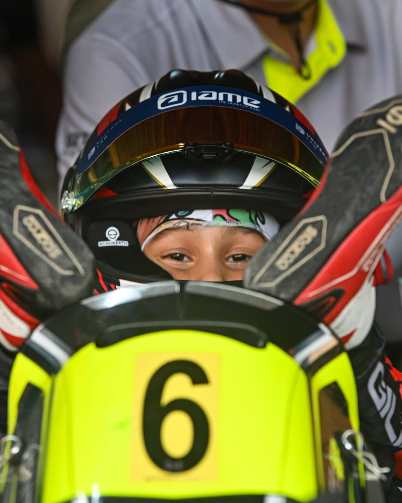 A Bambino driver's eyes through the open visor, gloves resting on the number 6 nassau panel