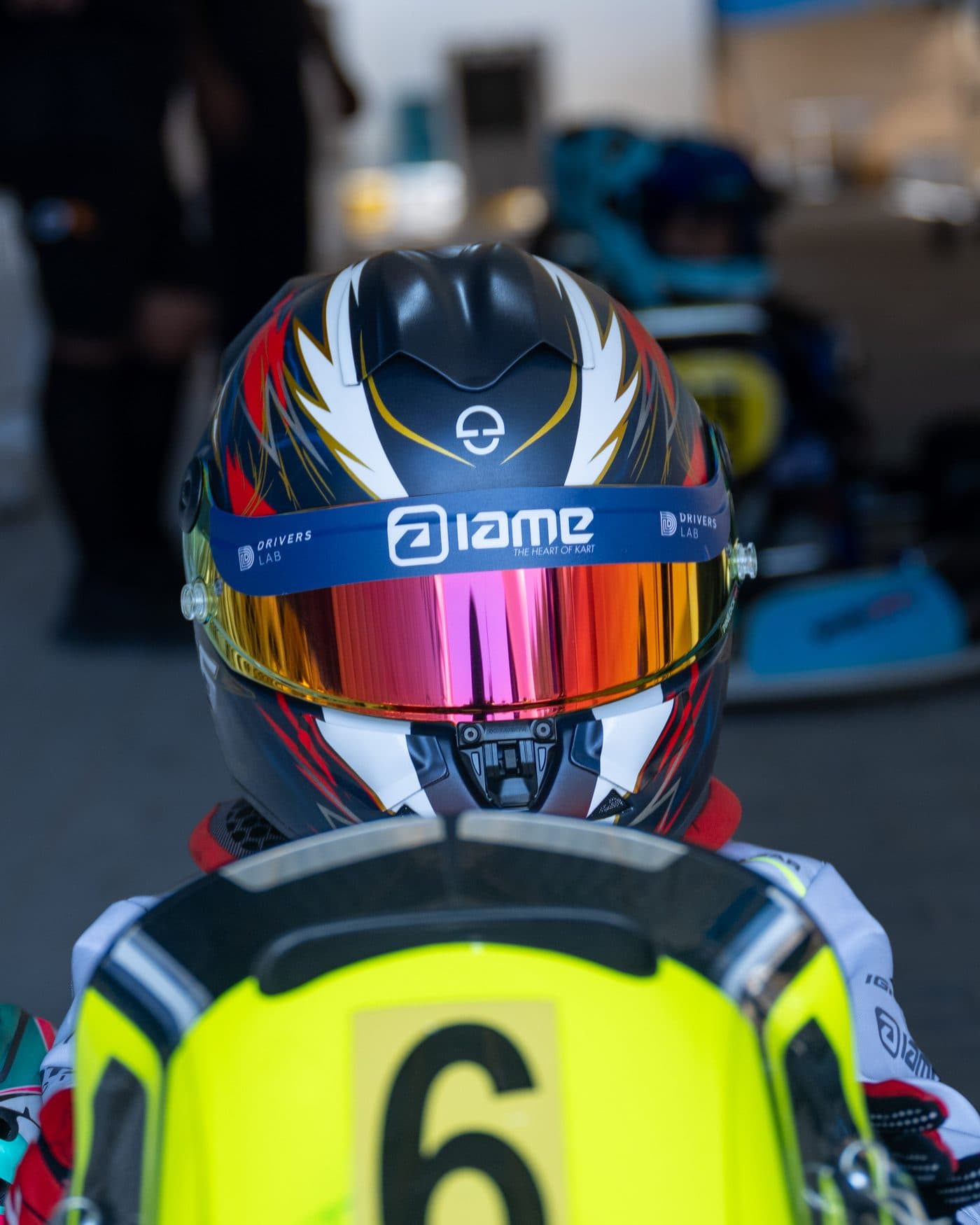 The back of a Bambino driver's helmet above the number 6 nassau panel, waiting on the grid