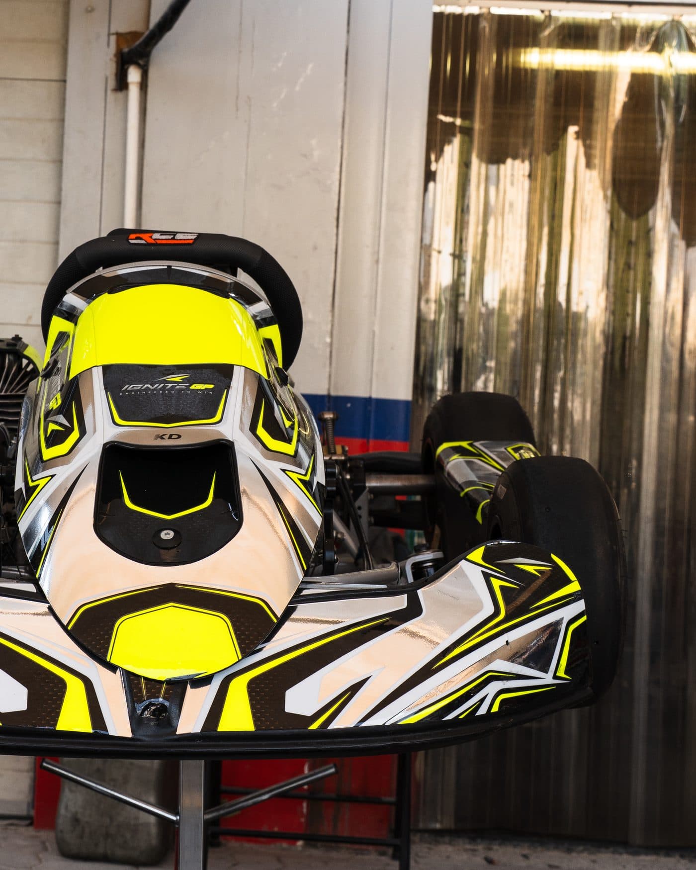 Ignite GP Bambino kart on a stand in the workshop, nose towards the camera, 'Engineered to win' on the nassau panel