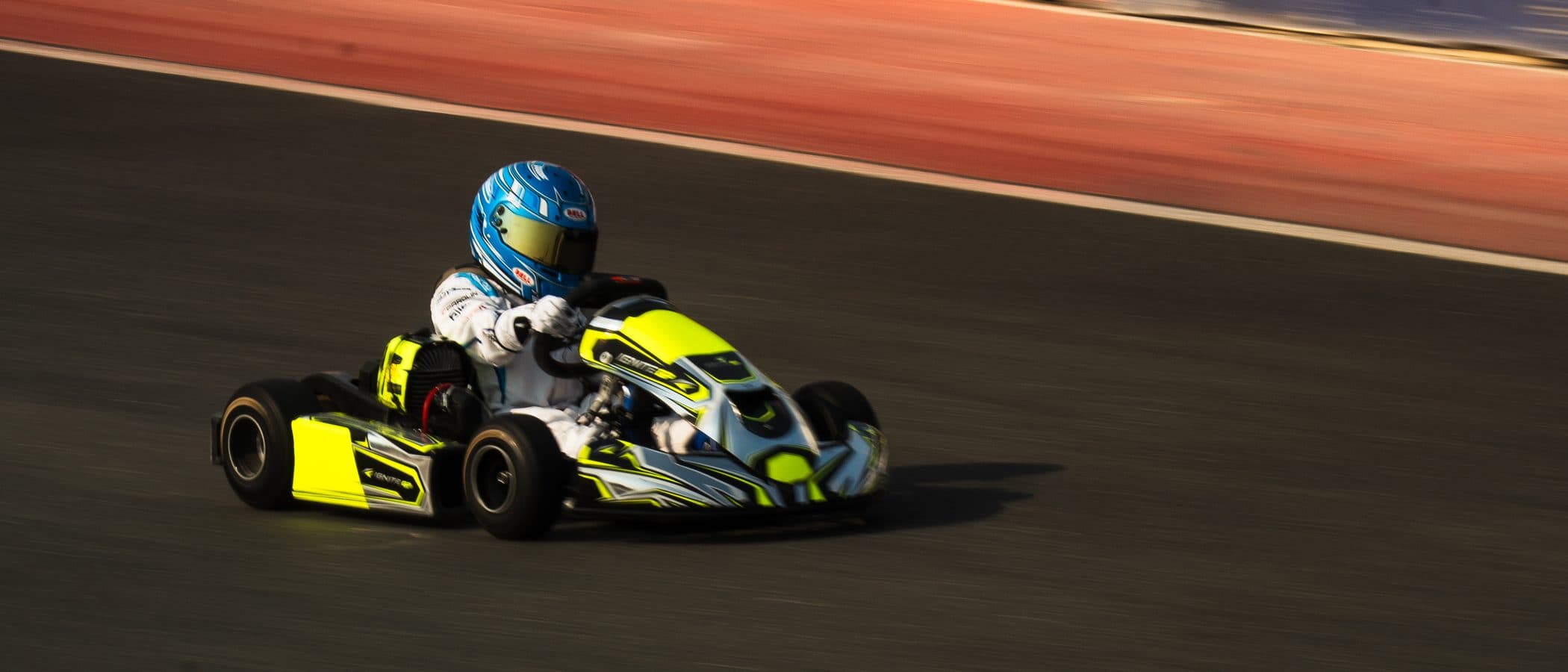 Bambino kart at full speed, panned so the track and barriers blur past