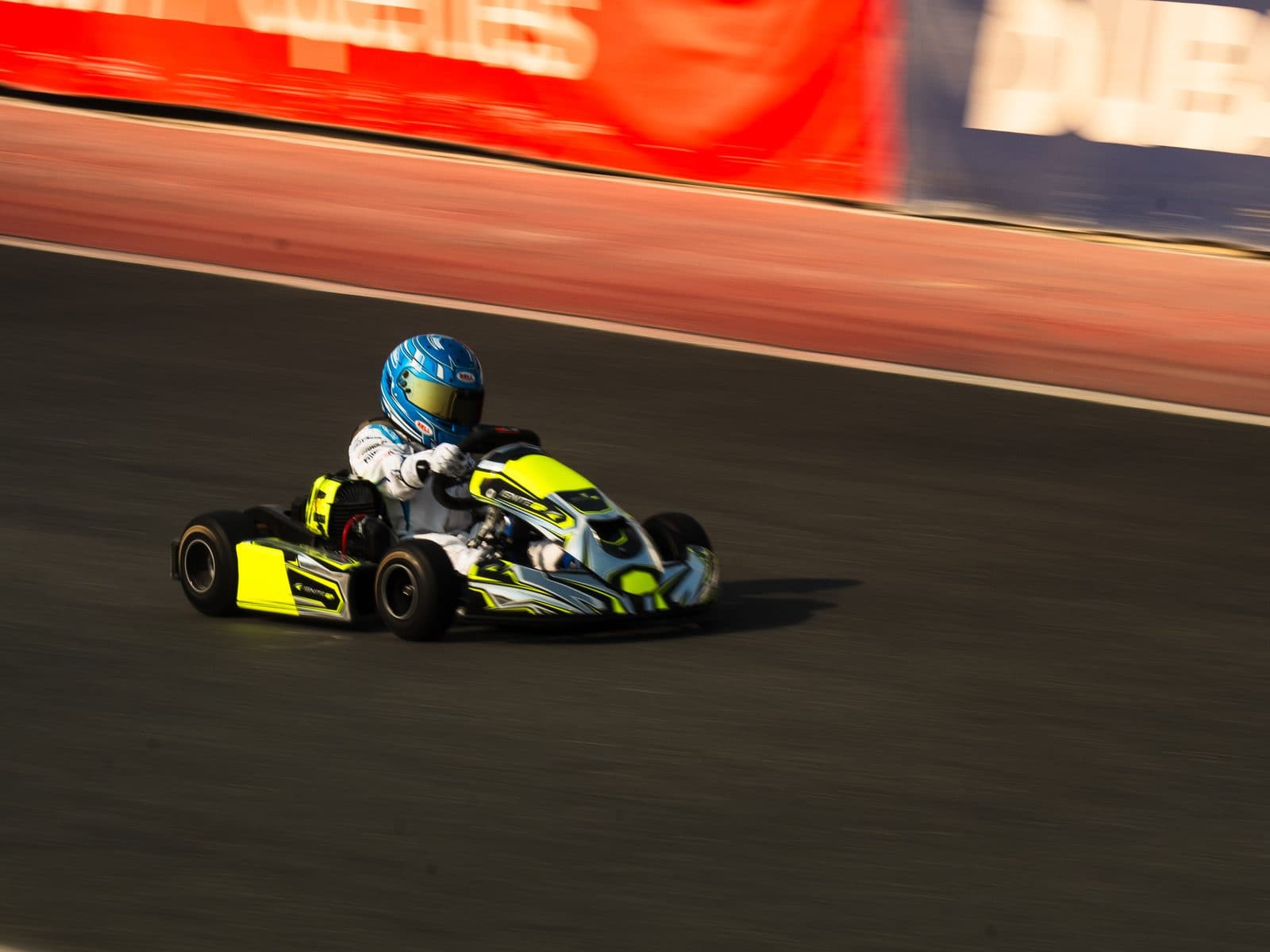 Bambino kart at full speed, panned so the track and barriers blur past