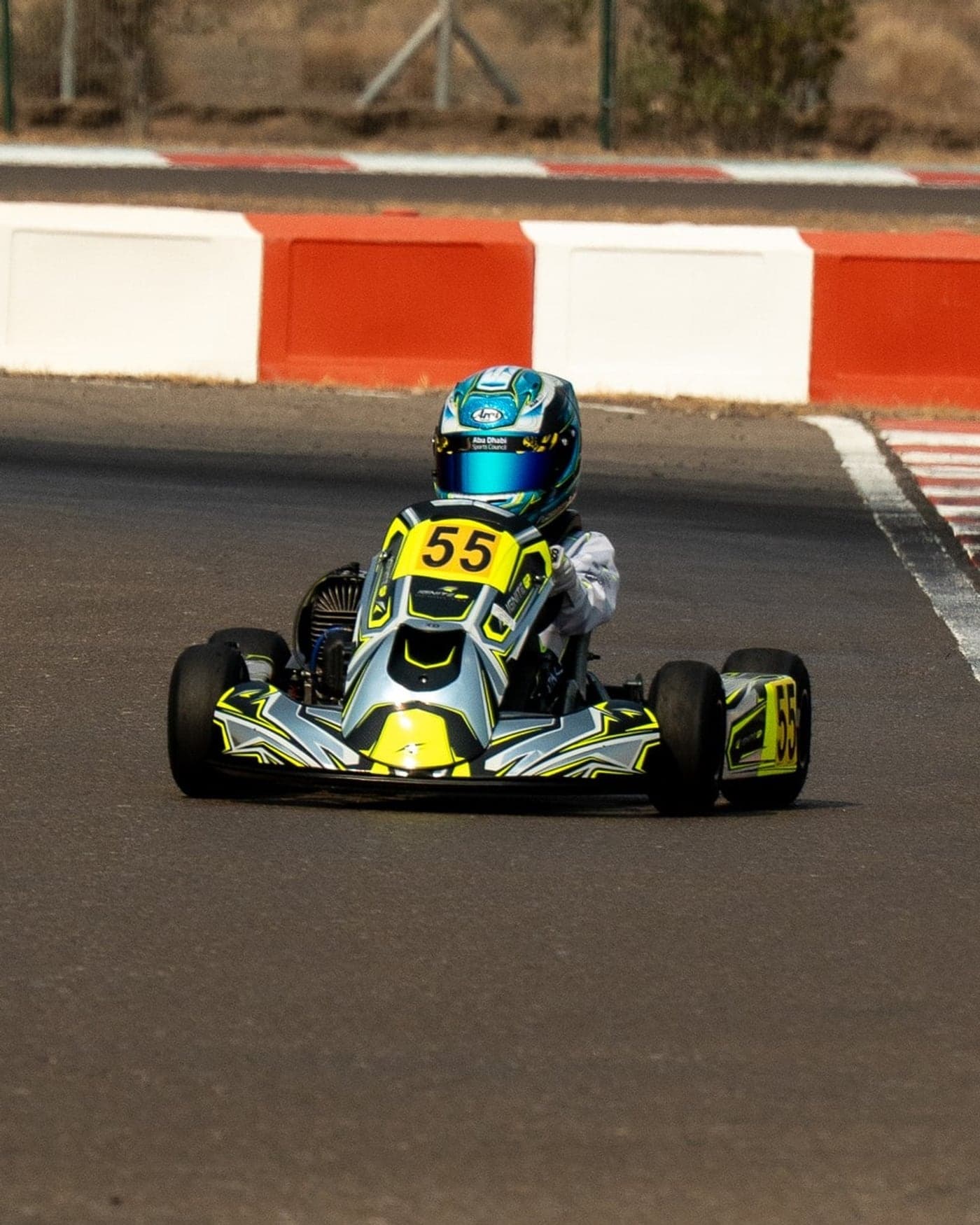 August Southall, no. 55, turning in past the red-and-white kerbs at Al Ain Raceway in the Ignite GP Bambino kart